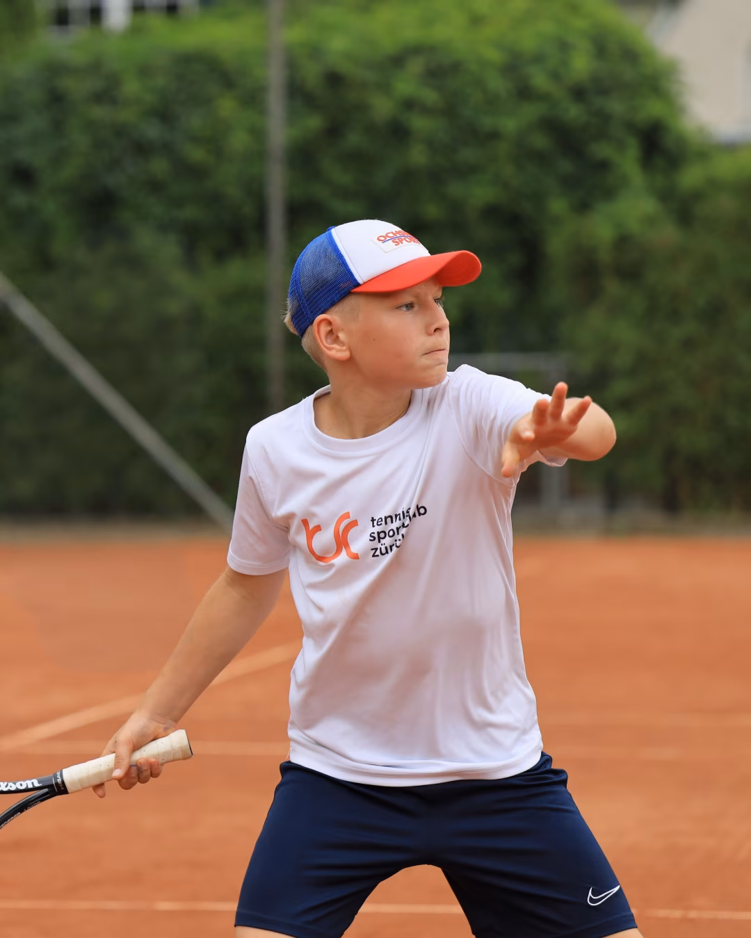 Junior tennis player hitting a forehand on a clay tennis court
