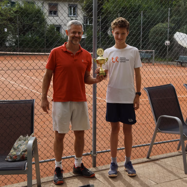 Zwei Tennisspieler halten eine goldenen Pokal in den Händen.