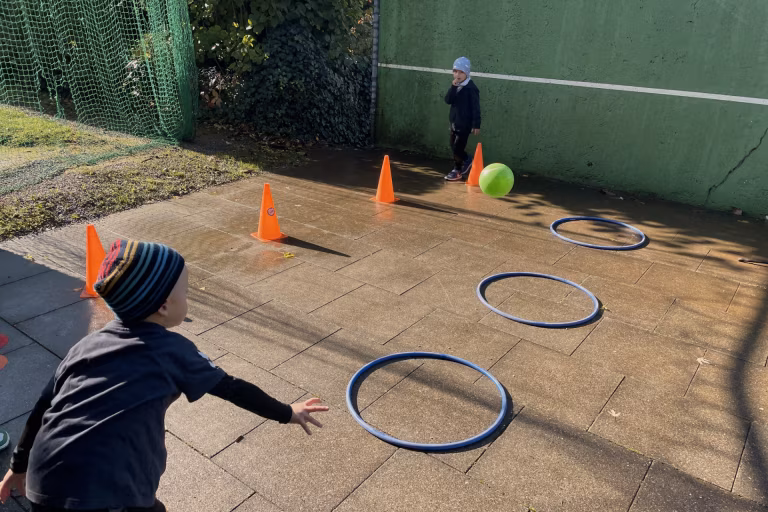 Zwei Kinder absolvieren ein Parcours mit Hütchen und Ringen.